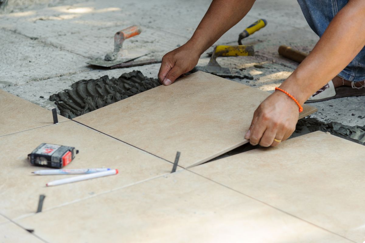 A man is installing tiles on a floor, demonstrating skill and attention to detail in his work.