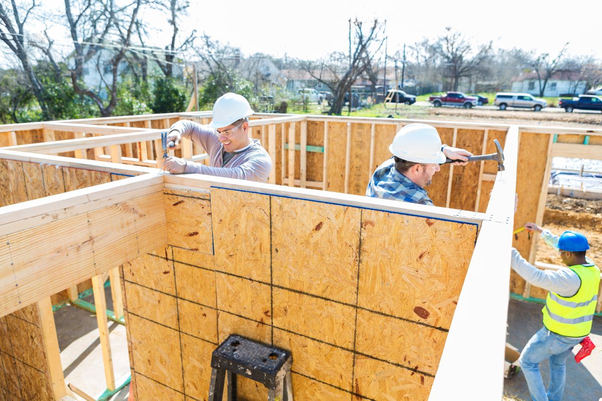Construction workers collaborating on a house project, using tools and equipment to build and enhance the structure.