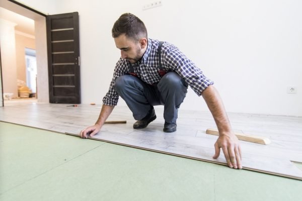 A man working on laminate floor installation in a room, highlighting a flooring service in Honolulu, HI.