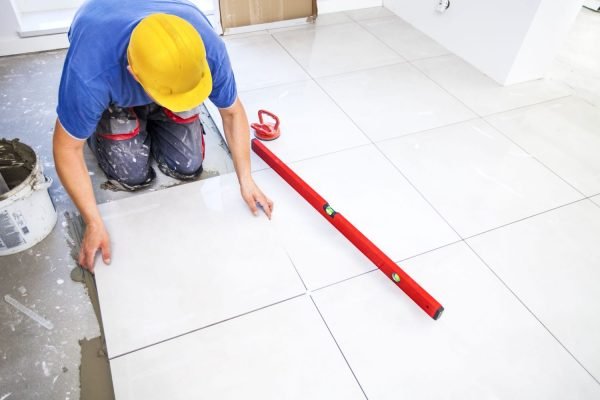 A man installing tiles on the floor, representing a tile flooring service in Honolulu, HI.